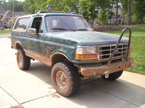 1996 Ford Bronco - This green Ford Bronco is covered in mud, indicating recent off-road use.