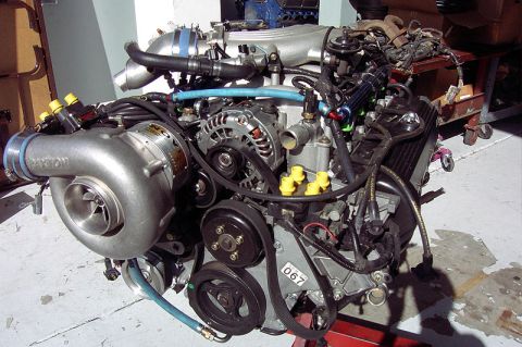 1992 Ford Crown Victoria - A modular V8 engine out of the vehicle on a stand, fitted with a polished Paxton centrifugal supercharger mounted low on the driver's side…