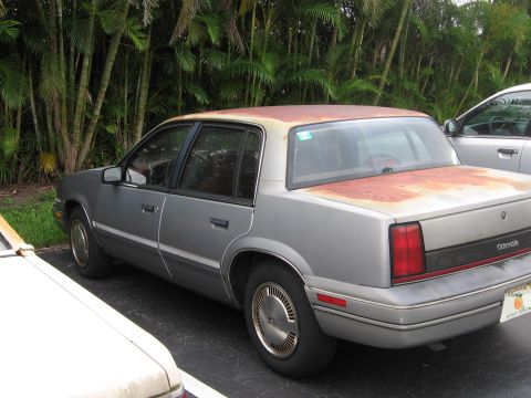 1991 Oldsmobile Calais - Side angle view. That rust gets worse with every picture.