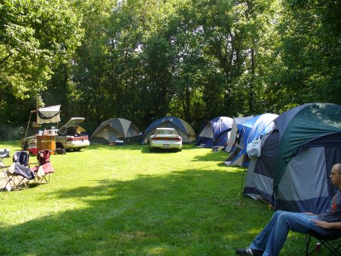 1991 Ford Probe - A campsite is set up with multiple tents and two cars parked on the grass.