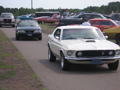 1989 Ford Mustang - White 1969 Ford Mustang at a drag strip, with a black Mustang and other vehicles visible.