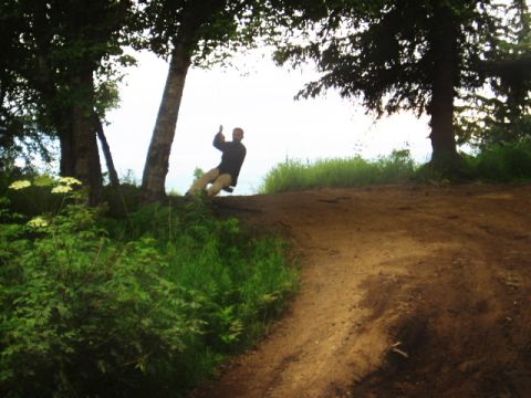 2000 Ford E350 - A person enjoys a swing on a dirt path surrounded by trees and greenery.