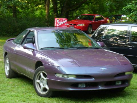 1991 Ford Probe - A purple 1991 Ford Probe is parked on a grassy area, with a red Ford Mustang visible in the background.