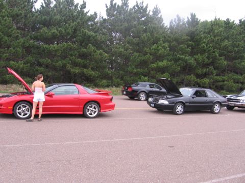 1989 Ford Mustang - A black 1989 Ford Mustang coupe is parked with its hood open, alongside other vehicles.