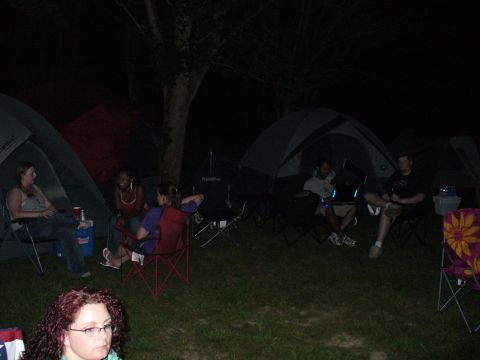 1991 Ford Probe - Campers relax in chairs around tents at a nighttime gathering.
