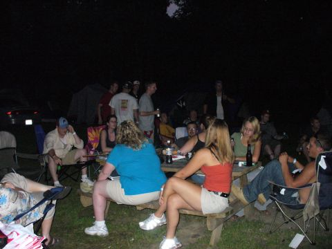 1991 Ford Probe - A nighttime gathering around a picnic table with several people, tents, and a car in the background.