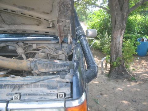 1990 Ford Bronco - The engine bay of a 1990 Ford Bronco is visible with the hood open and a snorkel installed.