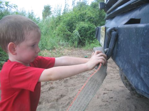 1990 Ford Bronco - A young boy prepares to tow a vehicle by attaching a strap to its rear bumper.