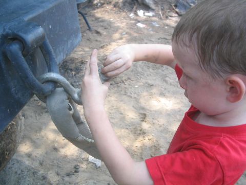1990 Ford Bronco - A child connects a tow strap to a vehicle's hitch, with Supermotors.net watermark visible.