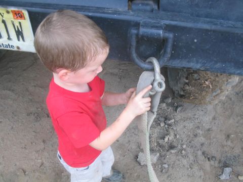 1990 Ford Bronco - Child helps connect tow strap to vehicle's rear hitch.