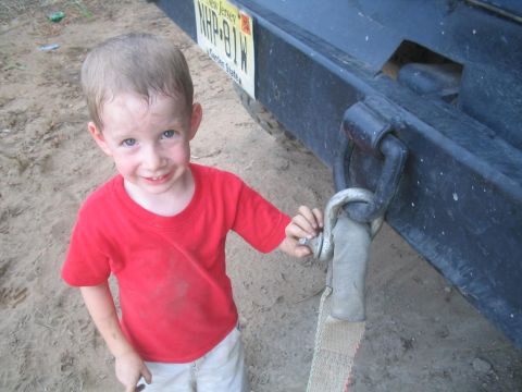 1990 Ford Bronco - A young child stands next to the tow hitch of a vehicle, holding onto a strap.