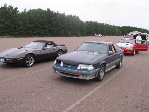 1989 Ford Mustang - A dark blue 1989 Ford Mustang is lined up on a race track with other vehicles.