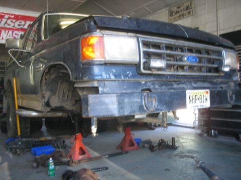 1990 Ford Bronco - Front view of a dark blue 1990 Ford Bronco undergoing repairs, with parts scattered around.