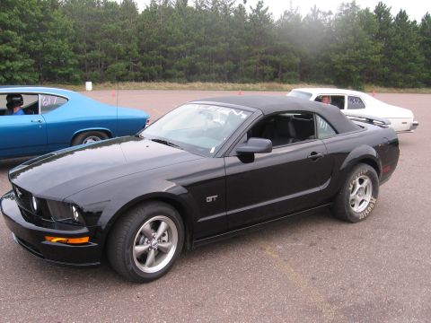 1989 Ford Mustang - A black convertible Mustang GT is parked on asphalt with other vehicles nearby.