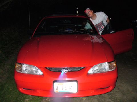 1991 Ford Probe - This red Ford Mustang from 1994 is shown from the front, with a person leaning out of the open passenger door.