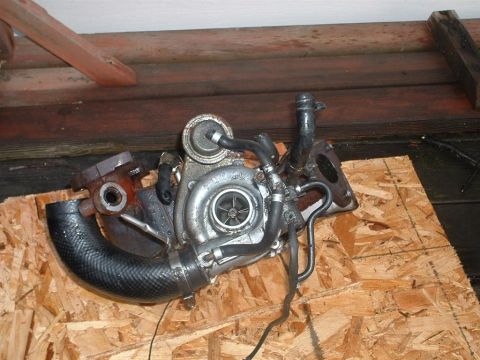 1991 Ford Probe - A turbocharger unit is shown, detached from a vehicle and placed on a piece of plywood.