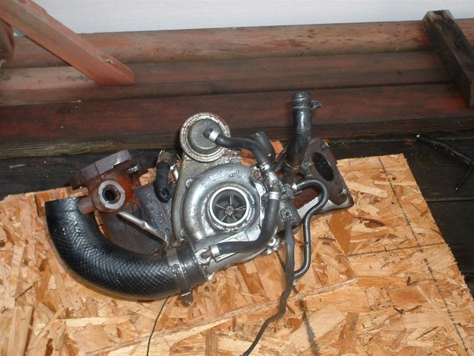 Turbocharger with black hose attached, resting on plywood