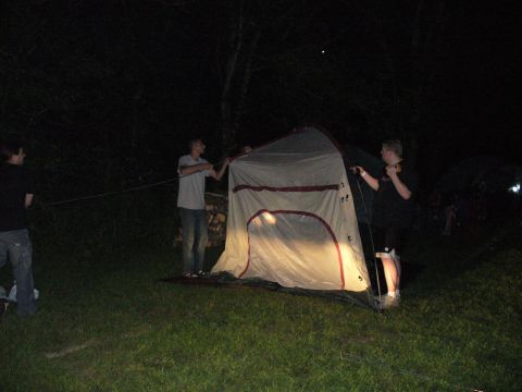 1991 Ford Probe - Several individuals are seen assembling a tent in a grassy area during nighttime hours.