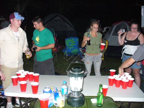 1991 Ford Probe - Friends enjoy a game of beer pong outdoors at night, with tents visible in the background.