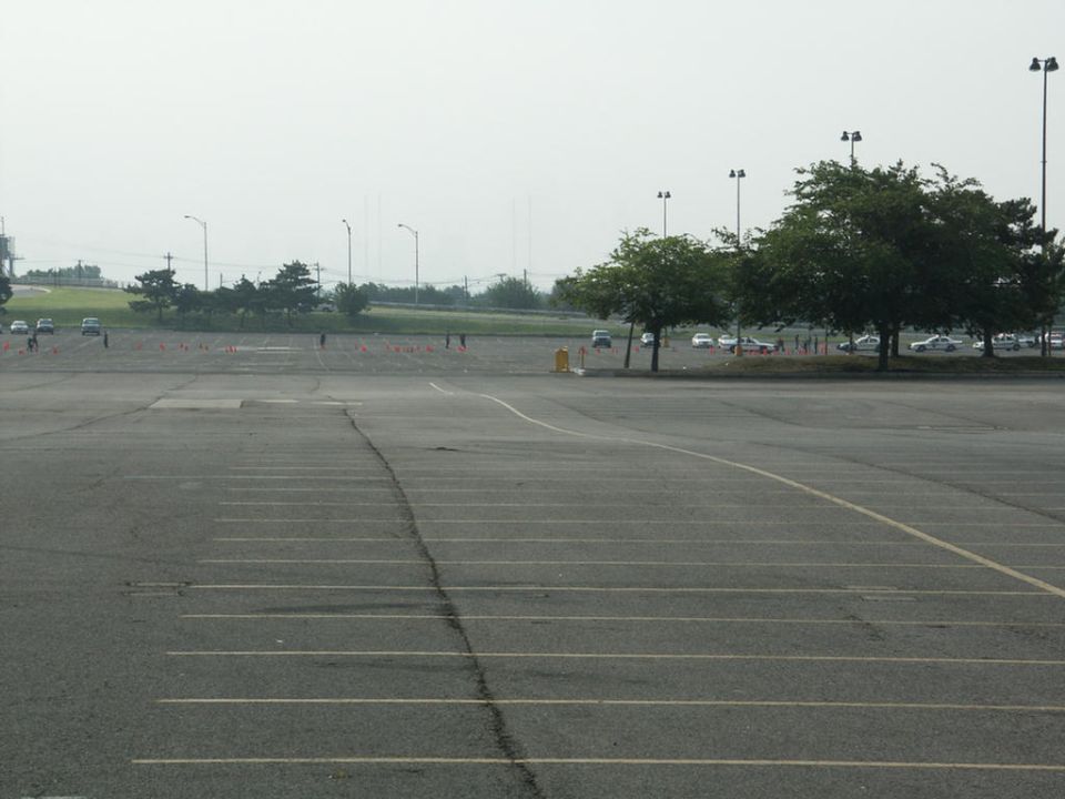 Empty parking lot with orange cones set up and cars parked in the distance