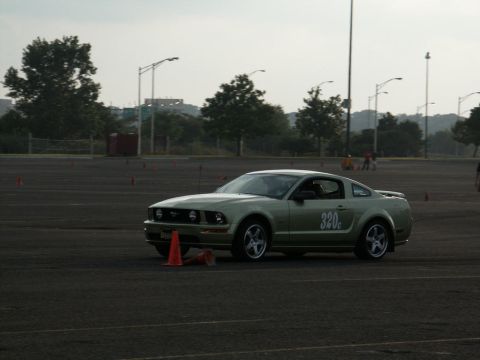 2001 Mercury Grand Marquis - A light green Ford Mustang is on a track with orange cones, possibly during a timed event.