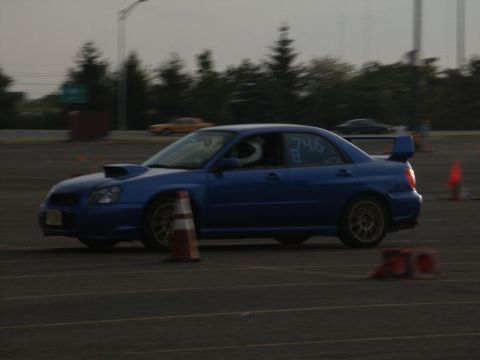 2001 Mercury Grand Marquis - A blue Subaru Impreza WRX STI navigates a course marked by traffic cones, with racing numbers visible on its side.