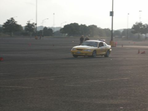 2001 Mercury Grand Marquis - A yellow coupe with a spoiler is seen on a track with cones marking the course.