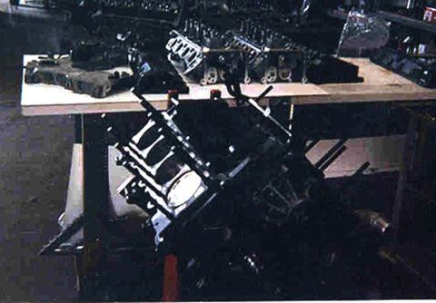 1992 Ford Crown Victoria - Dark shop photo of a freshly assembled V8 short block sitting on an engine stand, painted black with bare aluminum main girdle/valley area…