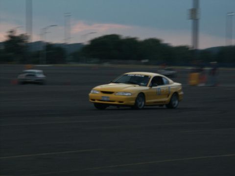 2001 Mercury Grand Marquis - Yellow 1994 Ford Mustang on track during an event, with another vehicle visible in the distance.