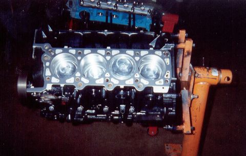 1992 Ford Crown Victoria - A freshly assembled V8 short block mounted on an orange engine stand, viewed down one bank with the head gasket laid on the deck and four d…