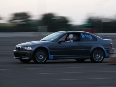 2001 Mercury Grand Marquis - A BMW M3 E46 coupe with racing numbers is captured in motion on a track, its side profile.