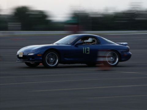 2001 Mercury Grand Marquis - A blue sports car with the number 113 on its door races on a track, blurring with motion.