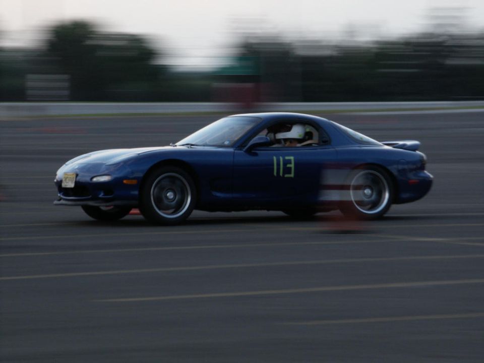 Blue sports car with number 113 on door, seen from the side on a track