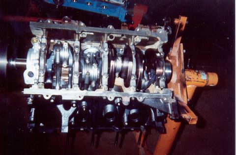 1992 Ford Crown Victoria - V8 short block inverted on an orange engine stand with the oil pan off, showing the installed crankshaft, main bearing caps and connecting…