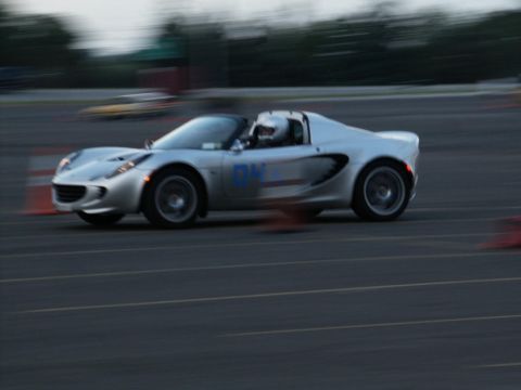 2001 Mercury Grand Marquis - A silver Lotus Elise is captured in motion on a race track, with orange cones visible.