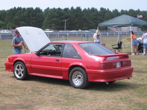 1989 Ford Mustang - A red 1989 Ford Mustang coupe is parked on grass with its hood open, showing a race number on the window.