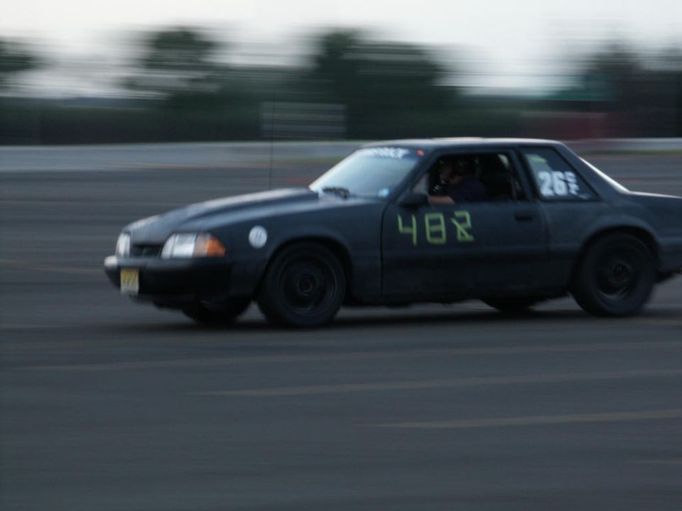 Black 1987 Ford Mustang race car with numbers 482 and 26 on doors and window