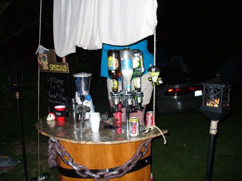 1991 Ford Probe - A temporary bar is set up outdoors with various drinks and accessories, with a car visible in the background.