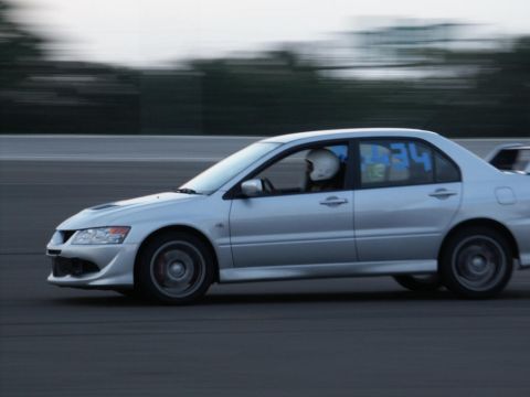 2001 Mercury Grand Marquis - A silver sedan with a driver wearing a helmet is captured in motion on a race track.