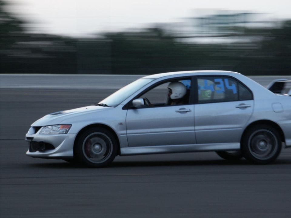 Silver sedan with racing numbers on the window driving on a track