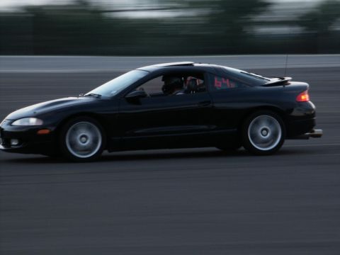 2001 Mercury Grand Marquis - A black coupe with racing numbers is captured in motion on a dark asphalt track.