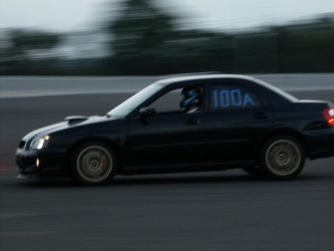 2001 Mercury Grand Marquis - A black sedan with racing numbers on the window is captured in motion on a track.