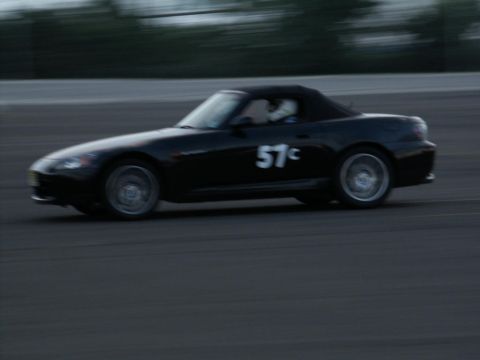 2001 Mercury Grand Marquis - Black convertible sports car with racing number 57c on its side, driving on a track.