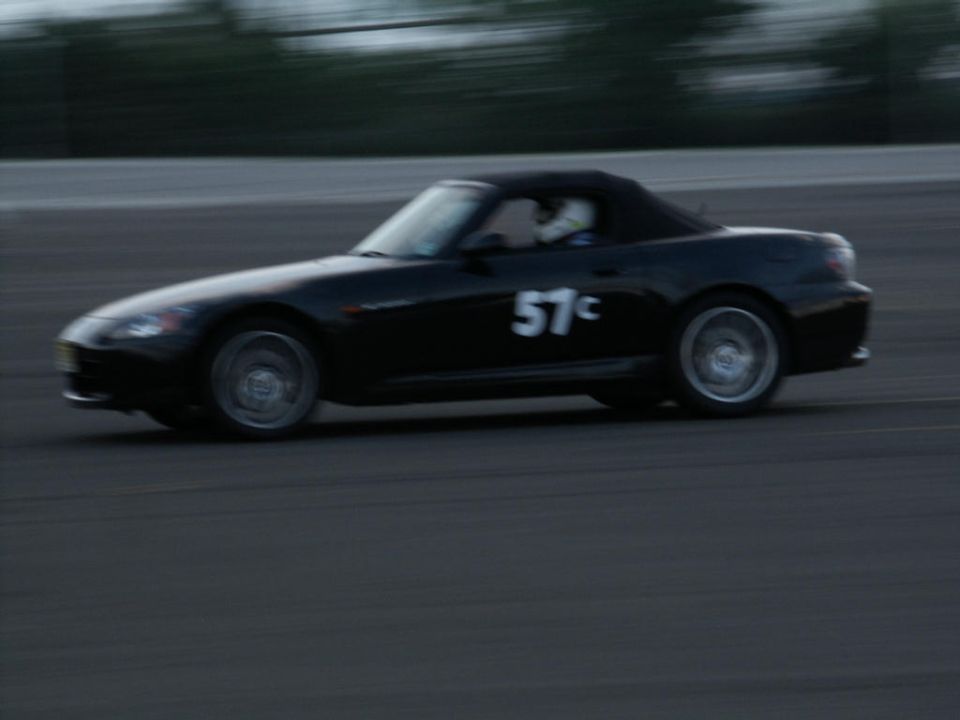 Black convertible sports car with racing number 57c on its side, driving on a track