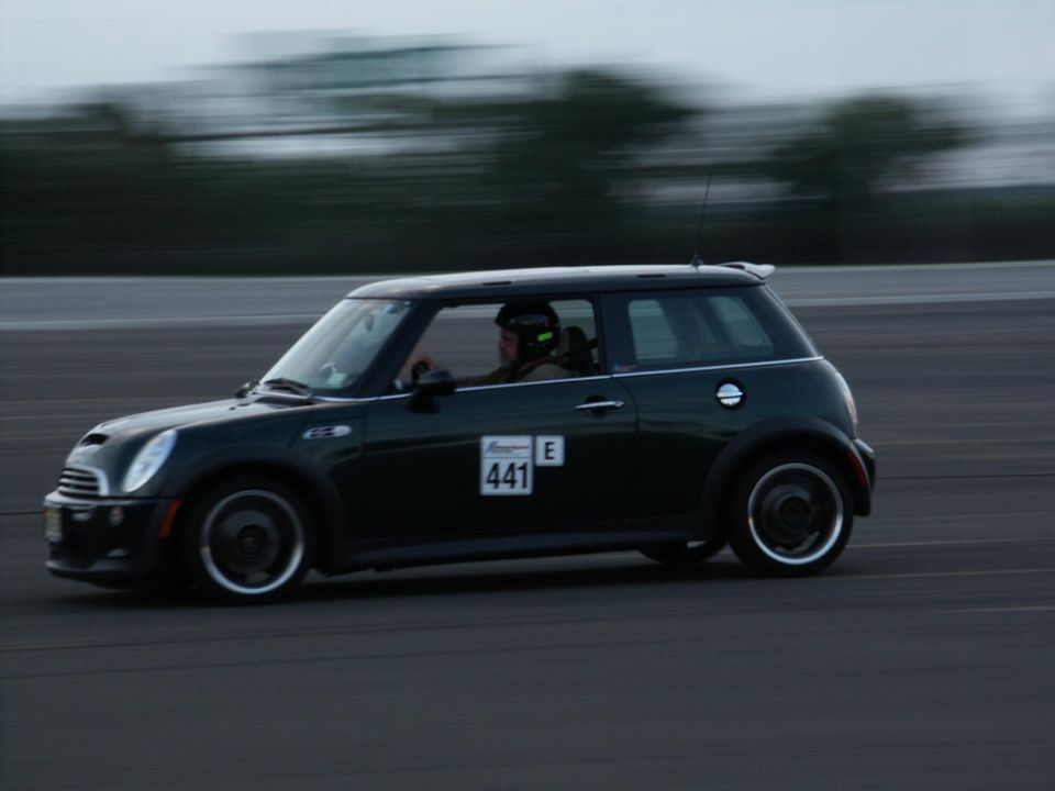 Dark green Mini Cooper with racing number 441 on the side, driving on a track