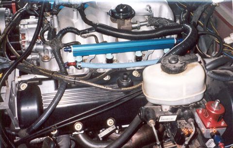 1992 Ford Crown Victoria - Close-up of a fuel-injected V8 engine bay showing blue anodized aluminum fuel rails with braided-line AN fittings feeding the injectors und…
