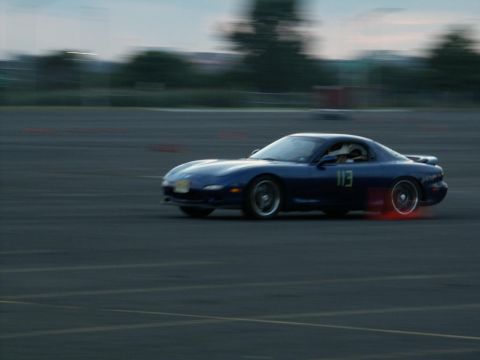 2001 Mercury Grand Marquis - A blue sports car is captured in motion on a track, with visible brake dust glowing red.