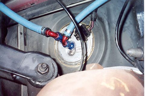 1992 Ford Crown Victoria - Underside view of a fuel tank sender unit with a plumbed-in aftermarket fuel setup: red and blue anodized AN fittings feeding light-blue br…