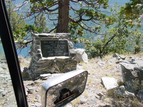 1986 Ford Bronco - A stone monument marks the Hell Hole Jeep Trail, with a damaged side mirror reflecting the rocky terrain.