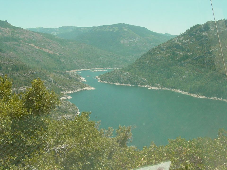 Scenic mountain lake with trees in foreground. Supermotors.net logo visible